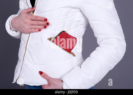 Frau trägt eine weiße wattierte Jacke mit einem roten Geldbeutel in der Tasche mit Reißverschluss Stockfoto