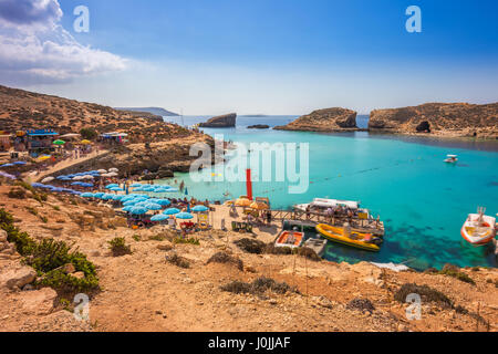 Comino, Malta - Touristen Menschenmenge bei Blue Lagoon, das klare türkisfarbene Wasser an einem sonnigen Sommertag mit klaren, blauen Himmel und Boote auf Comino Insel zu genießen, Stockfoto