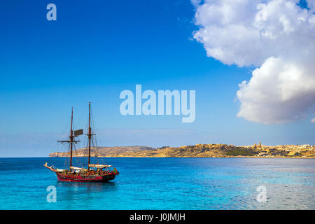 Blaue Lagune, Malta - altes Segelboot auf der Insel Comino neben der berühmten blauen Lagune mit der Insel Gozo und Stadt von Mgarr an der staatlich Stockfoto