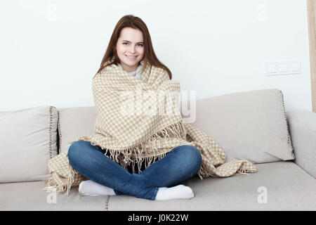 Mädchen sitzt auf dem Sofa unter den Teppich. Stockfoto