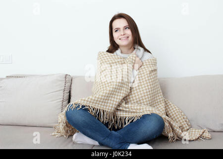 Mädchen sitzt auf dem Sofa unter den Teppich. Stockfoto