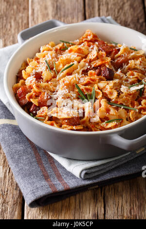 Farfaline Nudeln mit Tomaten, Speck und Parmesan Käse Nahaufnahme in einen Topf geben. Vertikal Stockfoto