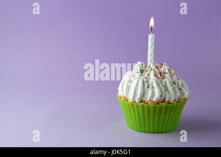 leckere Geburtstag Cupcake mit Kerze auf lila Hintergrund Stockfoto