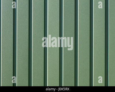 Grün metallic Zaun aus Wellpappe aus Stahlblech mit Senkrechtführungen. Wellpappe grün Eisen Blatthintergrund hautnah. Stockfoto