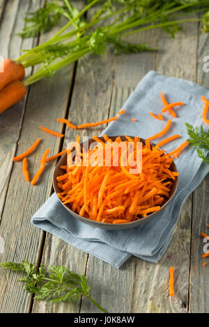 Rohe Bio Orange geriebenen Karotten in eine Schüssel geben Stockfoto