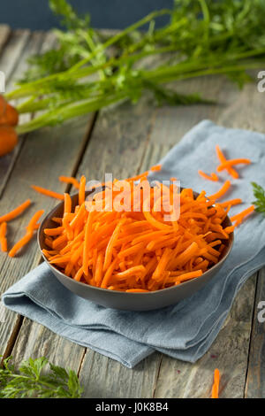 Rohe Bio Orange geriebenen Karotten in eine Schüssel geben Stockfoto