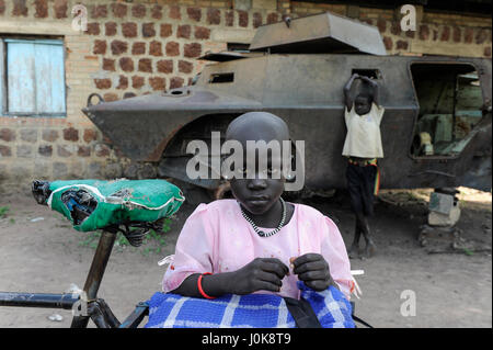 SÜDSUDAN, Lakes State, Stadt Rumbek, verlassenes Wrack des Panzerwagens Cadillac Gage V-150 Commando, hergestellt in den USA, aus dem zweiten sudanesischen Bürgerkrieg zwischen der südsudanesischen Volksbefreiungsarmee SPLA und der sudanesischen Armee SAF in ehemaligen SAF-Kasernen, Mädchen mit Fahrrad Stockfoto