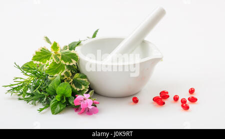 Mörtel, frische Kräuter und Pillen auf weißem Hintergrund Stockfoto