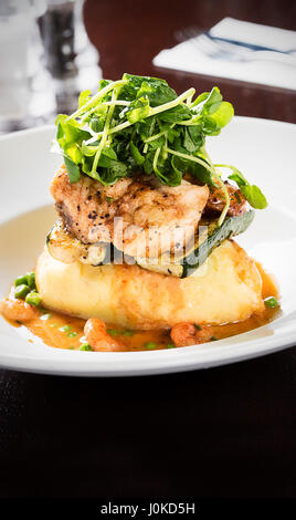 Fisch serviert auf Kartoffelpüree mit Salat Stockfoto