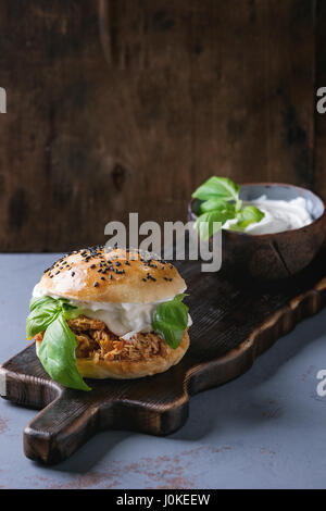 Hausgemachte Mini-Burger mit gezogener Huhn, Basilikum, Mozzarella-Käse und Joghurt-Sauce auf hölzernen Portion Board über graue Textur Hintergrund. Gesundes Fasten Stockfoto