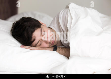 Gut aussehender Mann schlafend im Bett tragen Armband für Schlaf-tracking Stockfoto