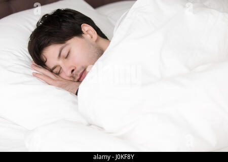 Schönen jungen Mann schlafen allein im weißen Bett, weiches Leinen Stockfoto
