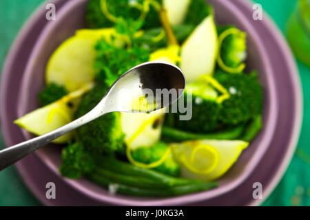 Nahaufnahme der Löffel mit Vinaigrette über pear, Brokkoli, grüne Bohnen Salat Stockfoto