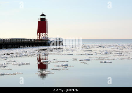 Ein roter Leuchtturm spiegelt sich in dem Eis Wasser des Lake Michigan an einem ruhigen Wintertag punktiert. Stockfoto