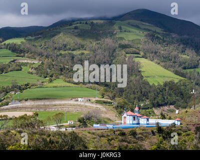 Nossa Senhora Monte Kapelle. Hoch gelegen über der Stadt, die kleine Kapelle in der Sonne leuchtet, wie ein Sturm die Hügeln hinter verschlingt. Stockfoto