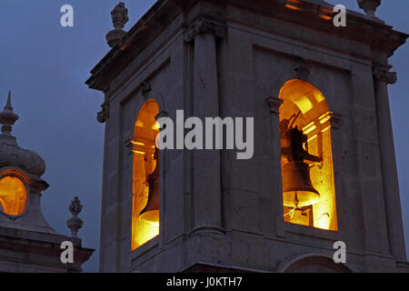 Nahaufnahme von einem Kirchturm in der Nacht mit den Glocken von Lichtern beleuchtet. Stockfoto