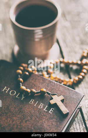 Rosenkranz, Bibel und Becher Wein auf Holztisch. Stockfoto