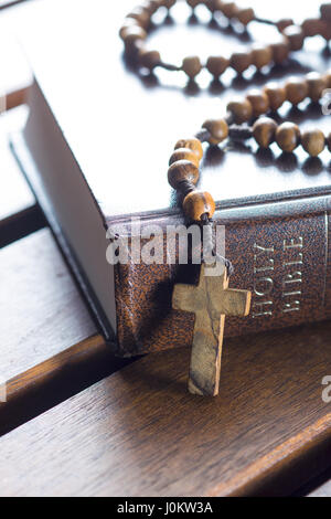Rosenkranz und Heilige Bibel auf Holztisch. Stockfoto
