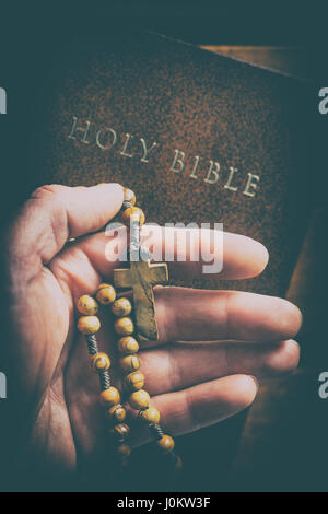 Rosenkranz in der Hand und Bibel. Stockfoto