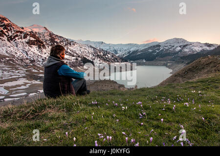 Ein Mann sitzt in den Bergen bewundern die Landschaft Landschaft von einem schönen See in den französischen Alpen Lac de Roselend Stockfoto