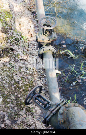 Das Ventil auf dem Rohr in der Nähe des Flusses in Herbsttag. Stockfoto