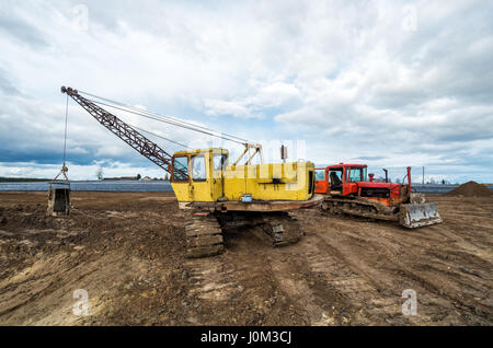 Die Bagger und alten roten Traktor im Feld Stockfoto