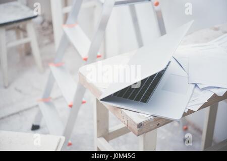 Das Innenministerium umgestaltet. Laptop-Computer, auf dem kleinen Holztisch als temporäre Schreibtisch. Baustelle und dem Computer. Stockfoto