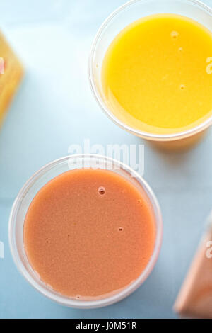 Erdbeer Banane und Orange mango Smoothie in Plastikbechern Stockfoto