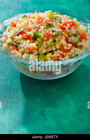 Glasschale mit Taboulé (Arabischer Salat) auf grün lackiert Textile Hintergrund mit Hintergrundbeleuchtung und Schatten Stockfoto