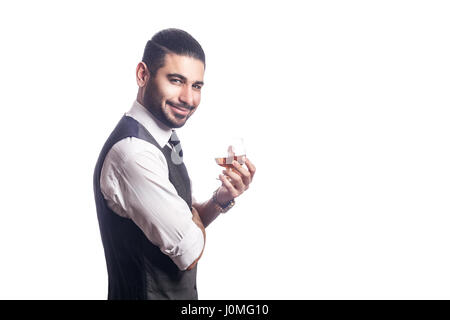 Gut aussehend bärtigen Geschäftsmann mit einem Glas Whisky. Glas und Blick in die Kamera Lächeln. Studioaufnahme, isoliert auf weißem Hintergrund. Stockfoto