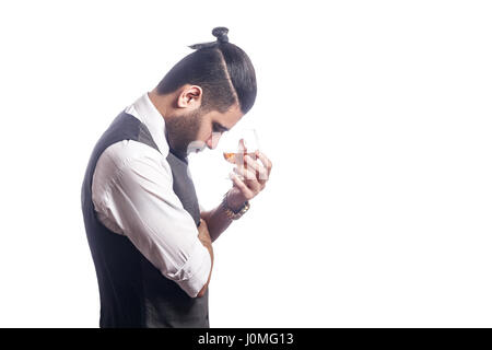 Gut aussehend bärtigen Geschäftsmann mit einem Glas Whisky. Seitenansicht, Glas halten und denken. Studioaufnahme, isoliert auf weißem Hintergrund. Stockfoto