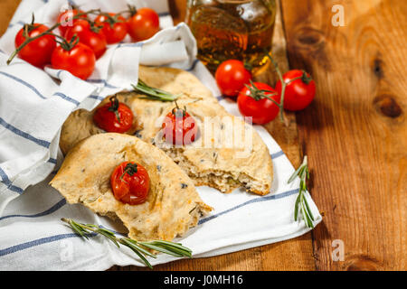 Traditionelle italienische Focaccia mit Tomaten und Rosmarin mit Olivenöl auf Holztisch Stockfoto