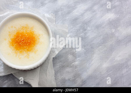 Hartweizengrieß (Farina) mit Milch und Rohrzucker in einer Keramikschale auf Papiertuch. Ansicht von oben. Stockfoto