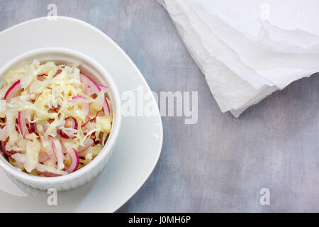 Platte und Töpfchen von Kohl und rote Zwiebel Salat über bemalte Textilien Hintergrund mit Papiertuch gefüllt. Draufsicht mit Textfreiraum. Stockfoto