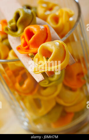 Getrocknet, roh Tortellini (mit Fleisch, Tomaten und Spinatfüllung) hintereinander auf einer hölzernen Gabel. Schräge Foto. Stockfoto