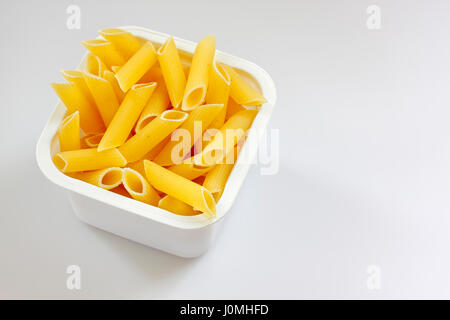 Rohe Penne Rigate Nudeln in der Kunststoff-Box auf hellem Hintergrund Stockfoto