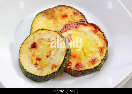 Drei gebratene Scheiben Zucchini auf Platte Stockfoto