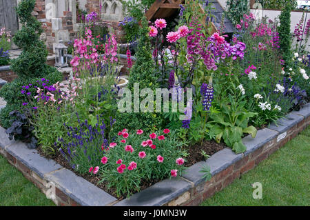 Bunte Pflanzen in einer erhöhten Blumenbett ein Patio-Garten Stockfoto