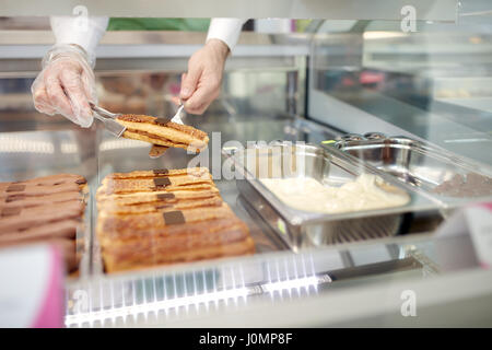 Nahaufnahme eines Verkäufers Händen herausnehmen Keks-Kuchen aus Showcase in Bäckerei Stockfoto