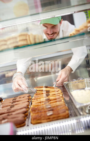 Arbeiter in der Bäckerei sorgfältig herausnehmen Keks-Kuchen aus der Vitrine Stockfoto
