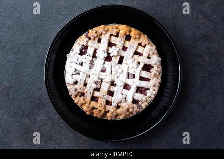 Köstliche Torte mit Kirschen, Puderzucker auf der schwarzen Platte Stockfoto