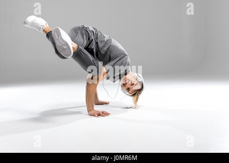 Junger sportlicher Mann im Kopfhörer tanzen und Lächeln in die Kamera Stockfoto