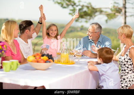 Sieg-Mädchen in einem Kartenspiel mit ihrer Familie Stockfoto