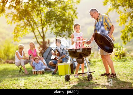 Enkelin machen Barbecue mit Großvater auf Campingplatz Stockfoto