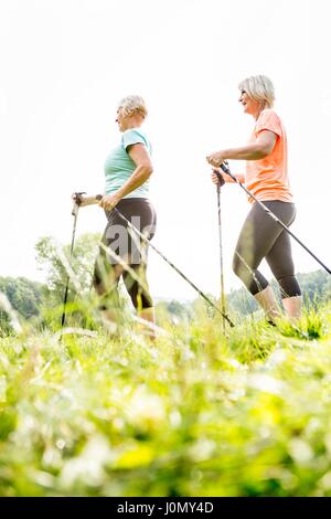 Zwei Frauen gehen in Gras mit Walking Stöcke. Stockfoto