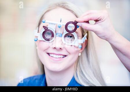Porträt der fröhliche junge Frau mit Augenuntersuchung im Optiker Shop, close-up. Stockfoto