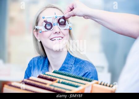 Fröhliche junge Frau mit Augenuntersuchung im Optiker Shop, close-up. Stockfoto