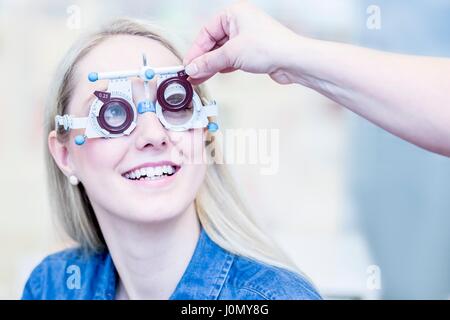 Fröhliche junge Frau mit Augenuntersuchung im Optiker Shop, close-up. Stockfoto