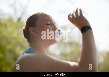 Frau trinkt aus Flasche Wasser. Stockfoto