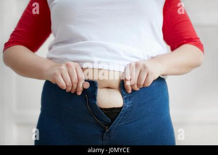 Frau versucht, Schaltfläche "Jeans über Bauch. Stockfoto